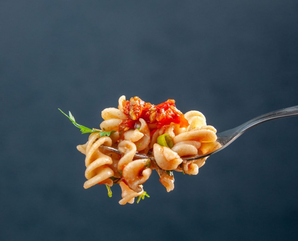 front-view-rotini-pasta-fork-dark-isolated-surface-free-space