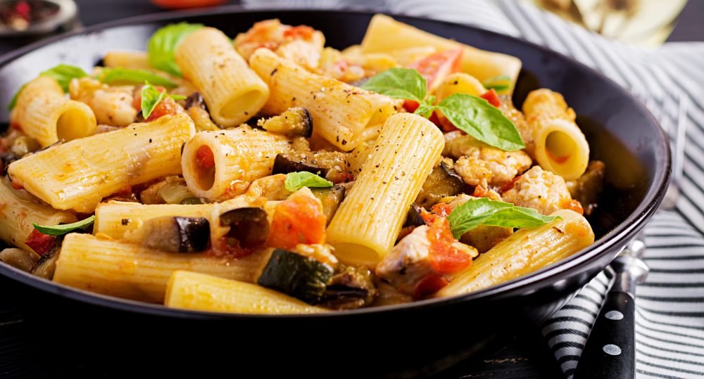 Rigatoni pasta with chicken meat, eggplant in tomato sauce in bowl. Italian cuisine.