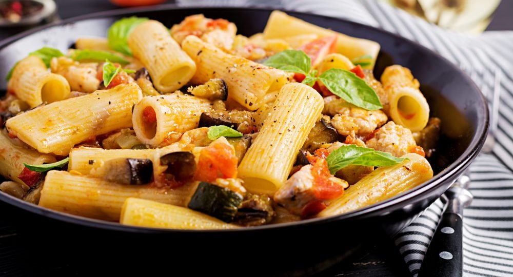 Rigatoni pasta with chicken meat, eggplant in tomato sauce in bowl. Italian cuisine.