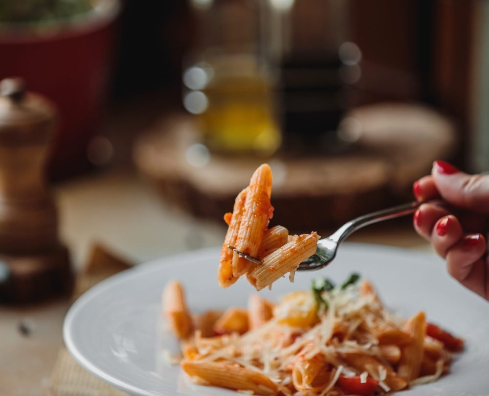 side view of fork with pasta with tomato sauce and parmesan cheese