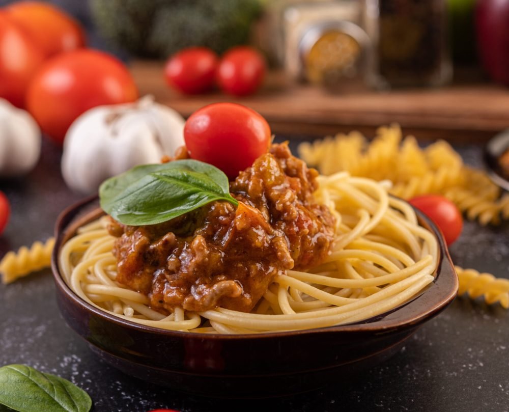 Spaghetti saute in a gray plate with tomatoes and basil